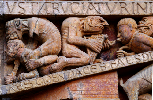 Détail d'un fronton d'église montrant des figures diaboliques exerçant leur emprise sur des damnés.